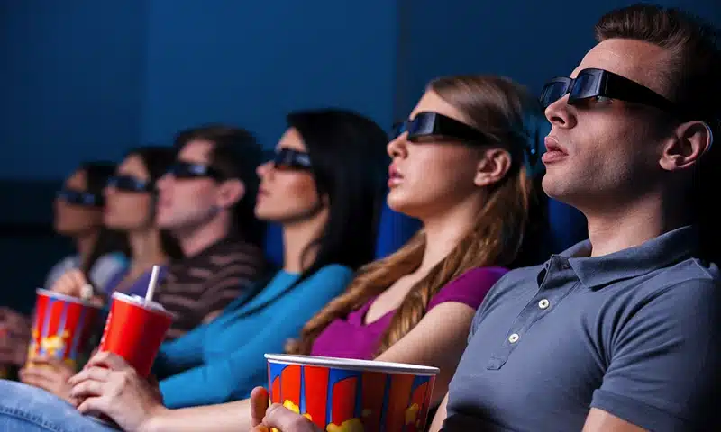 Espectadores disfrutando de una experiencia de entretenimiento inmersivo con una película 3D en el cine.